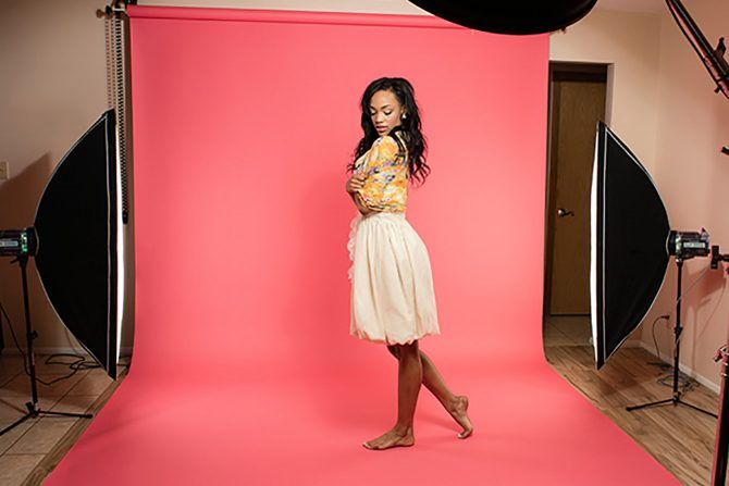 a woman standing in front of a pink backdrop