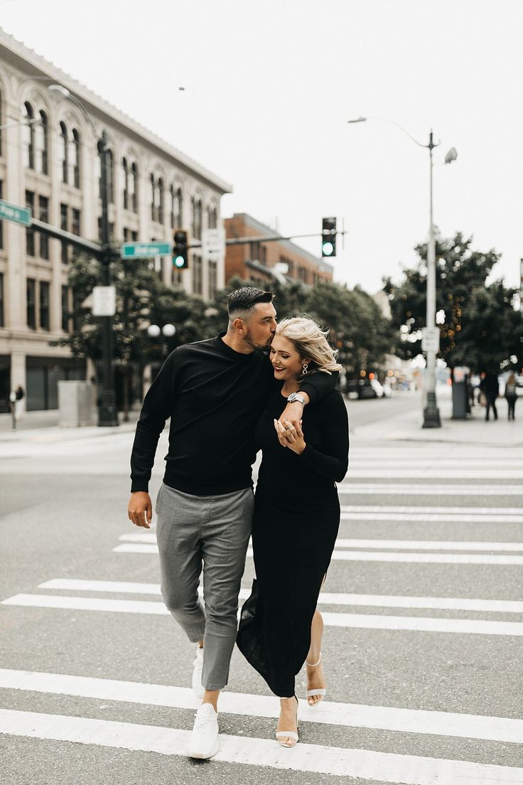 a man and woman walking across a crosswalk in the middle of a city street