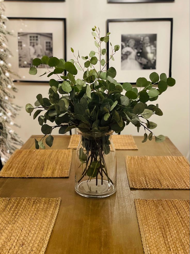 a vase filled with greenery sitting on top of a wooden table