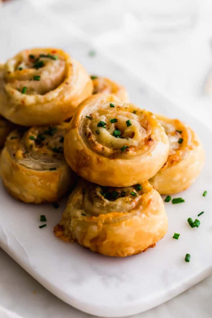 several small pastries on a white plate with green garnishes and sprinkles