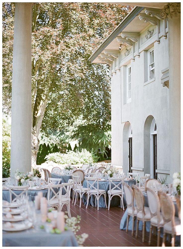 an outdoor dining area with tables and chairs set up for a formal function in front of a large white building