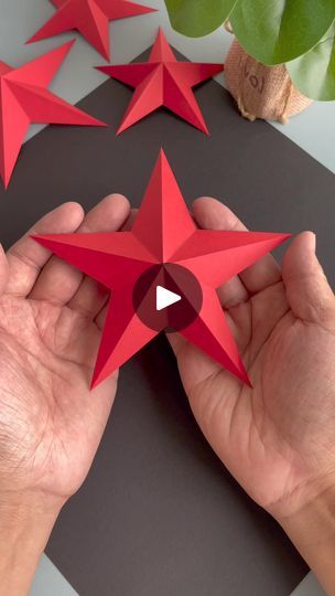 two hands are holding red origami stars