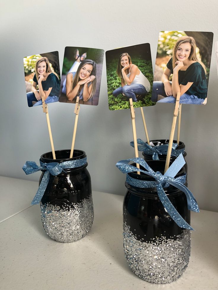 two vases with pictures on sticks sticking out of them, one is black and the other is silver