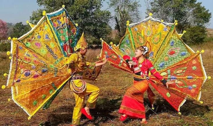 two women are holding colorful umbrellas in the grass