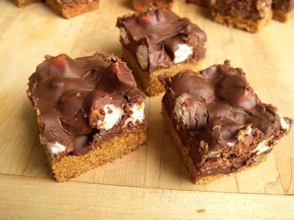 several pieces of chocolate dessert sitting on top of a wooden cutting board next to each other