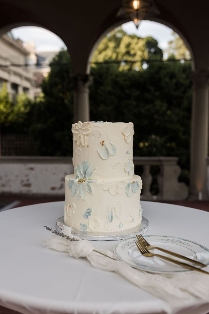 a white wedding cake sitting on top of a table next to a knife and fork