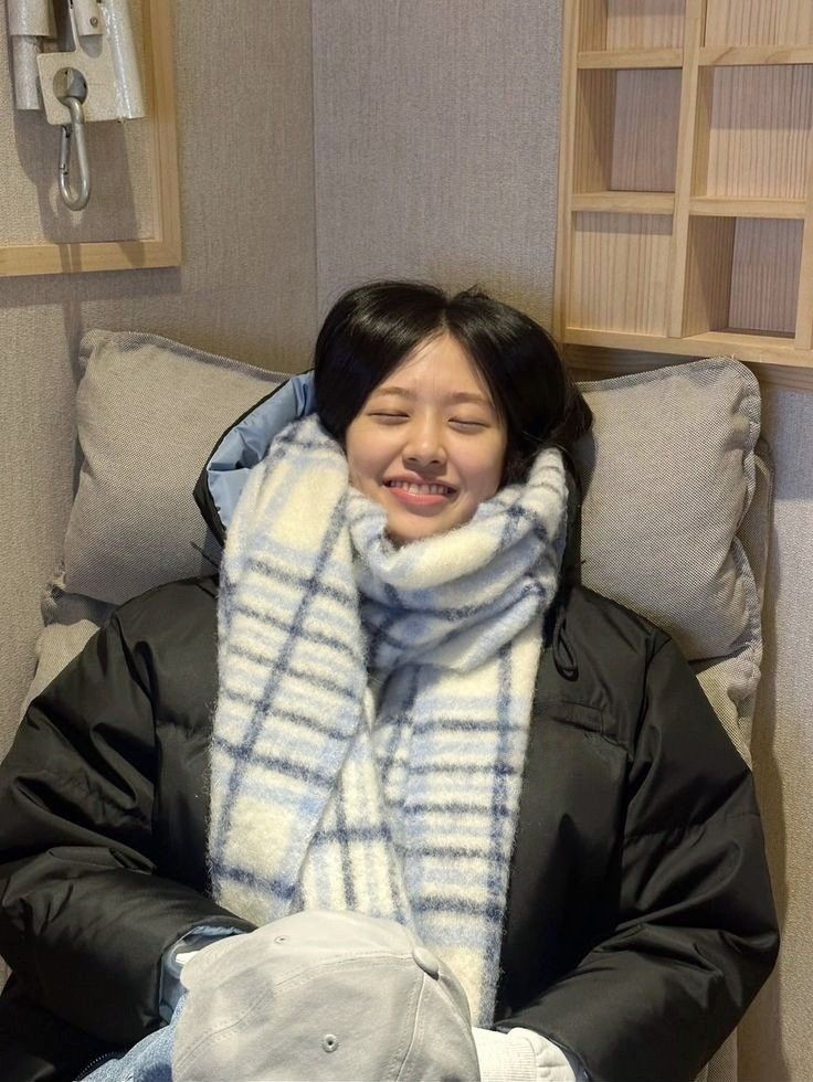 a woman laying in bed with a blanket on top of her head and smiling at the camera