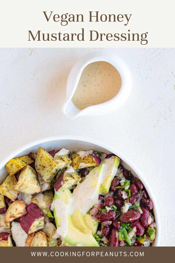 a white bowl filled with vegetables and dressing next to a spoon on top of it