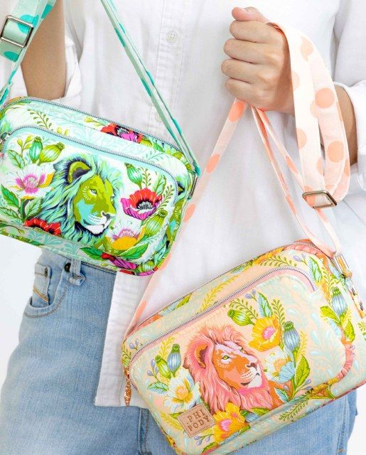 a woman is holding two colorful purses in her hands and one has an animal design on it