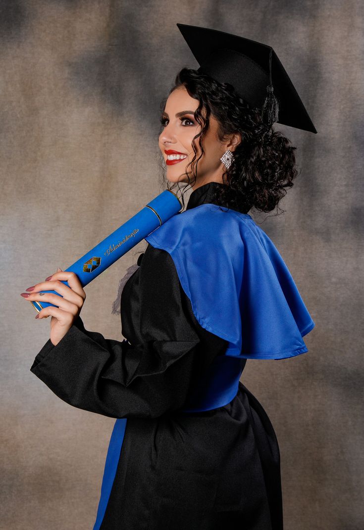 a woman wearing a graduation gown and holding a giant blue toothbrush