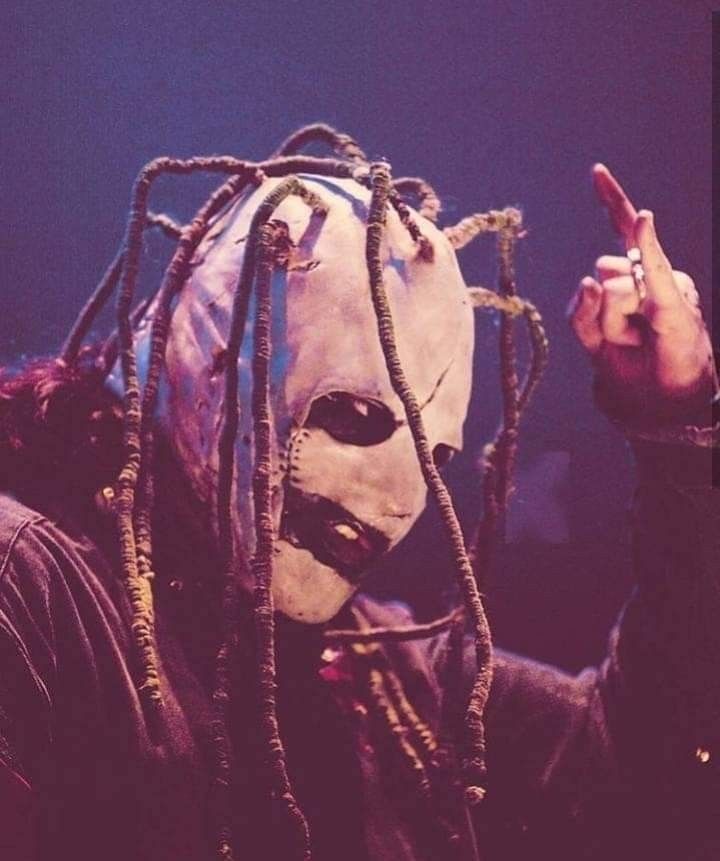 a man with dreadlocks and a mask on holding up his finger to the camera