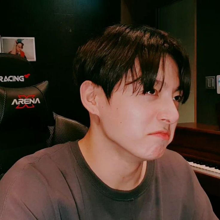 a young man sitting in front of a piano with his head turned to the side