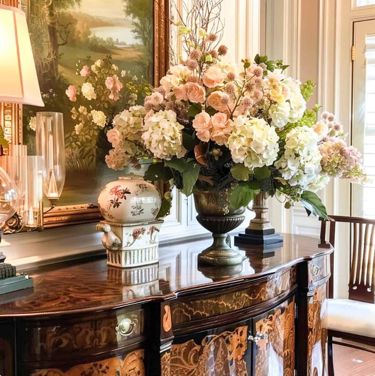 a vase filled with flowers sitting on top of a wooden table next to a lamp