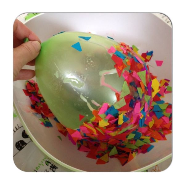 a green balloon filled with confetti in a white bowl