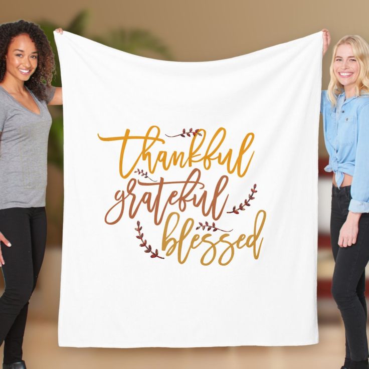 two women holding up a white towel with the words grateful and an orange floral design