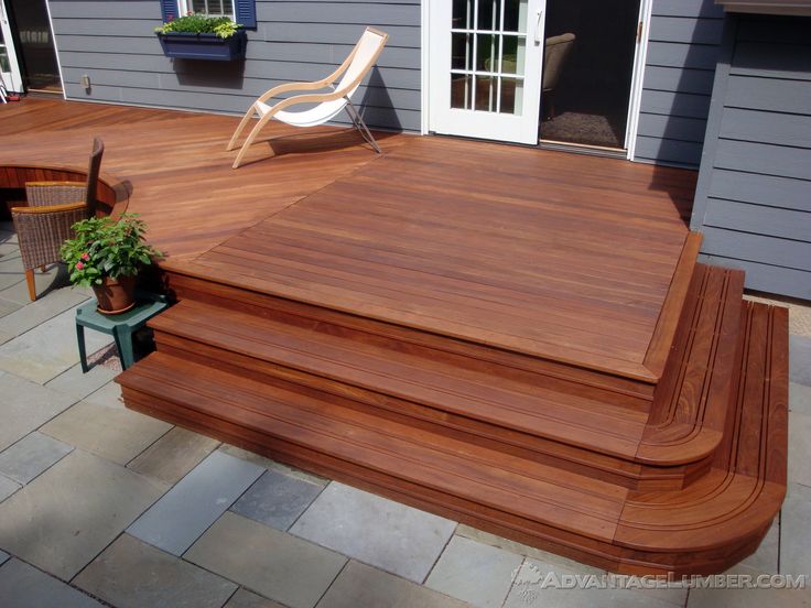 a wooden deck in front of a house with a chair and potted plant on it