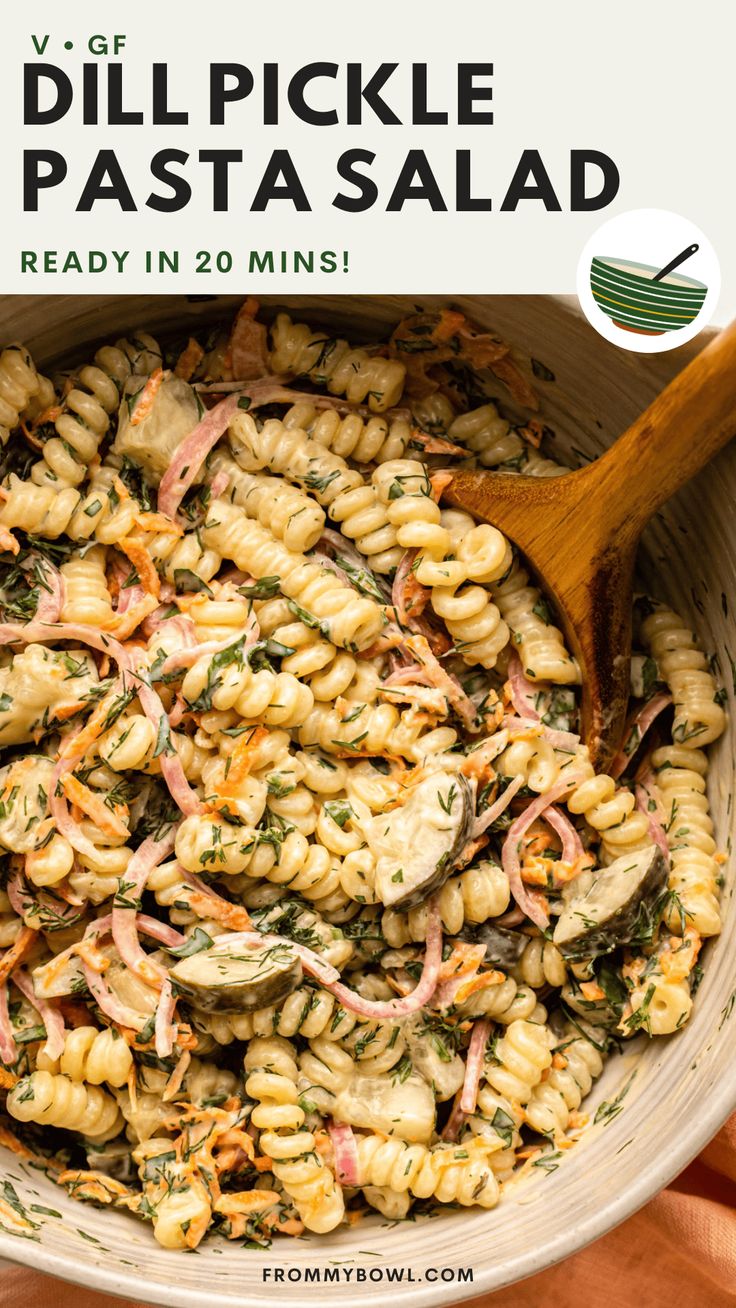 a bowl filled with pasta and vegetables next to a wooden spoon