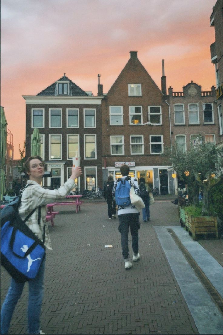 a woman taking a selfie with her cell phone in front of some buildings at sunset