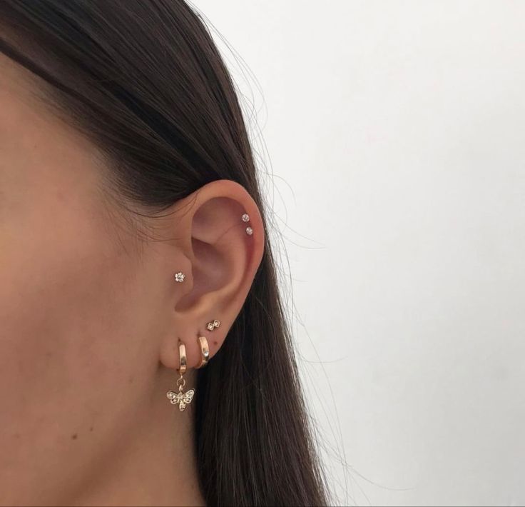 a close up of a woman's ear wearing gold earrings with small stars on them