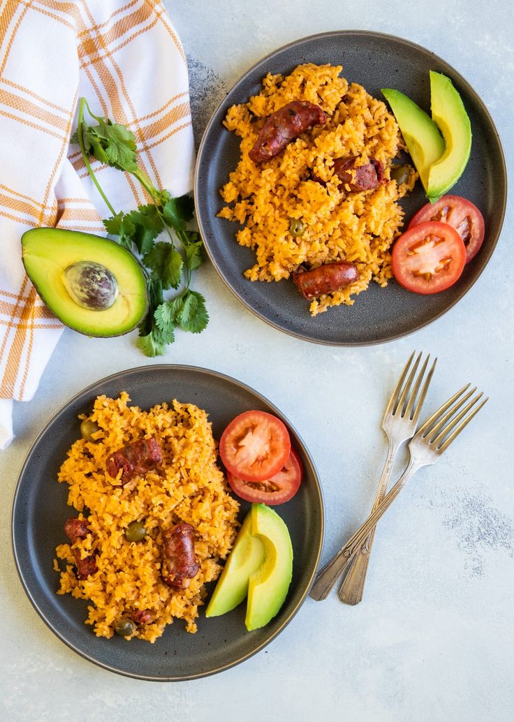 two black plates topped with rice, avocado and tomatoes