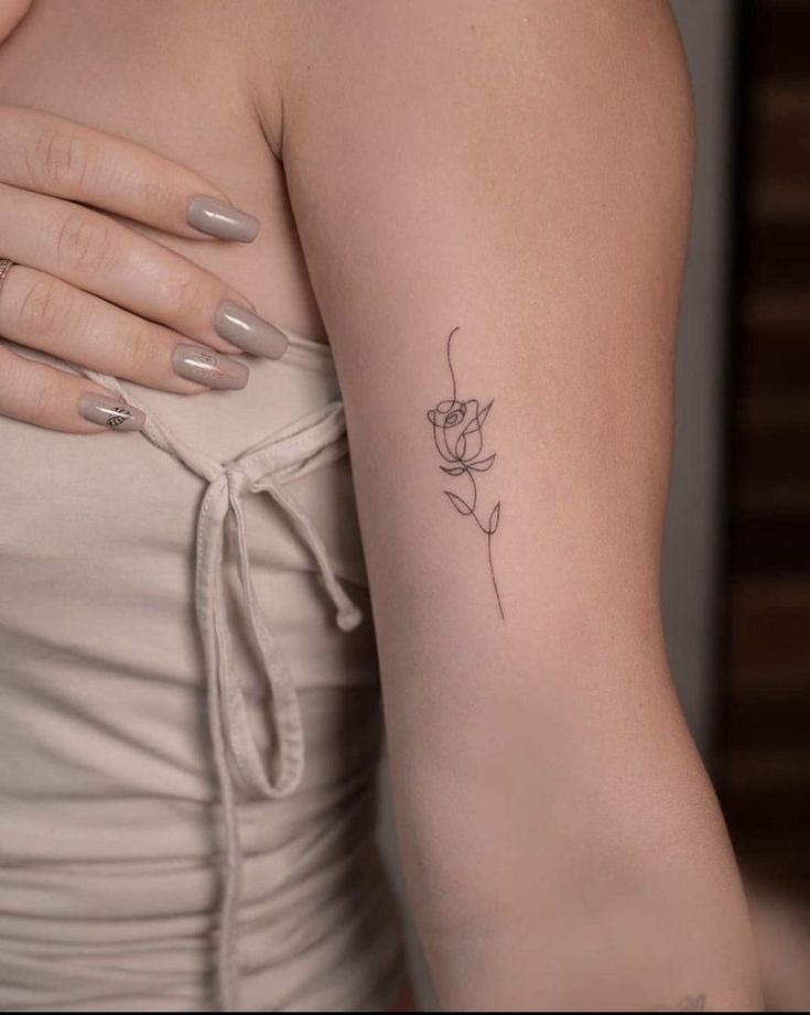 a woman's arm with a small flower tattoo on the left side of her arm