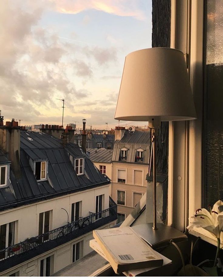 a lamp is sitting on the window sill next to a book and some papers