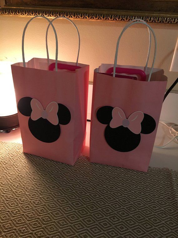 two pink bags with minnie mouse ears on them sitting on a table next to a lamp