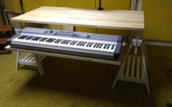 an electronic keyboard sitting on top of a wooden table next to a microphone and chair