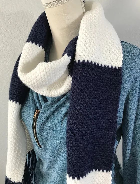 a mannequin wearing a blue and white sweater with a striped scarf on it