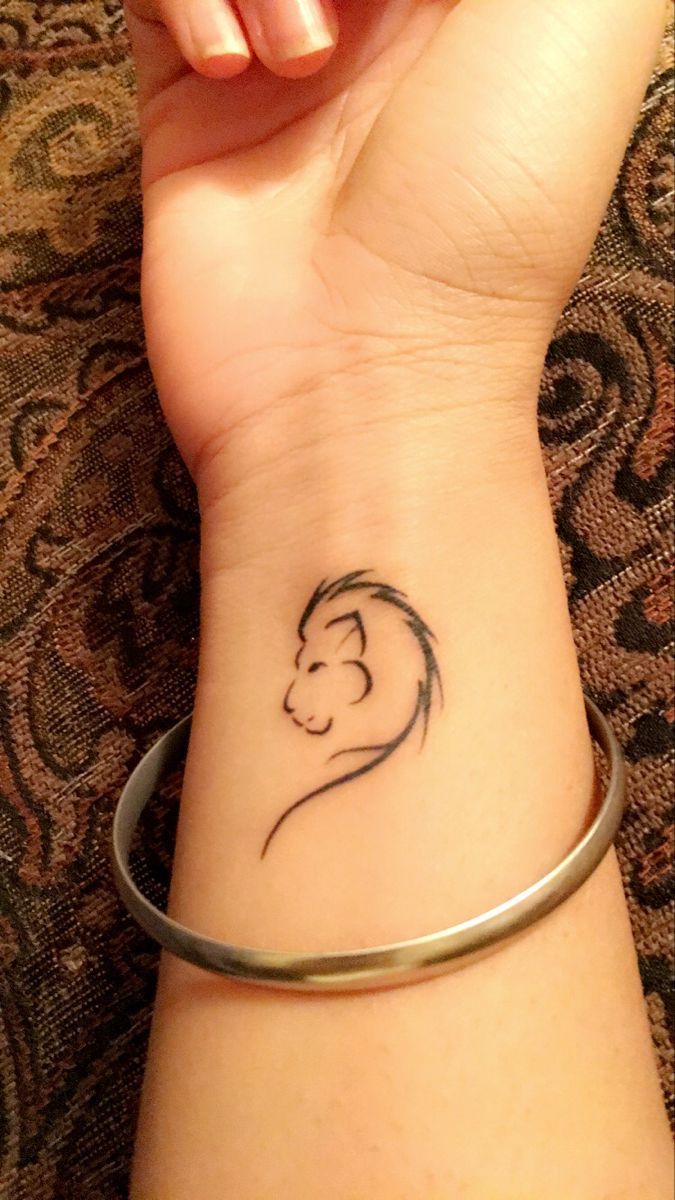 a woman's wrist with a small tattoo of a lion on the left arm