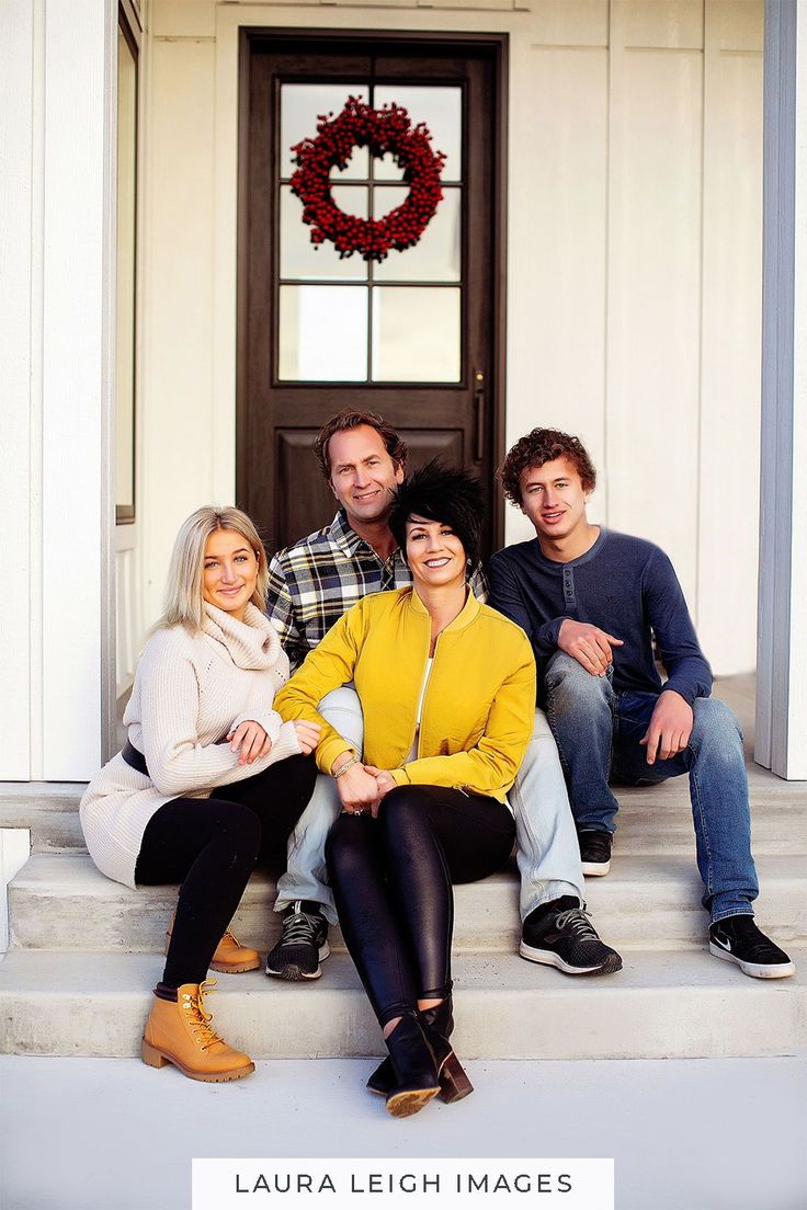 three people sitting on the steps of a house with their arms around each other and smiling