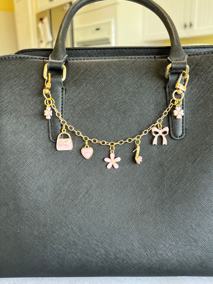 a black purse with gold chains and charms hanging from it's handles on a table