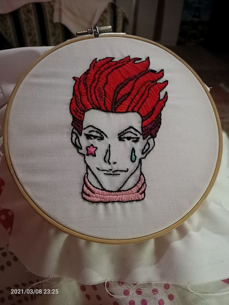 a close up of a embroidery on a pillow with a person's face and red hair