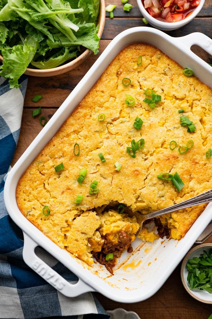 a casserole dish with meat and vegetables in it on top of a wooden table