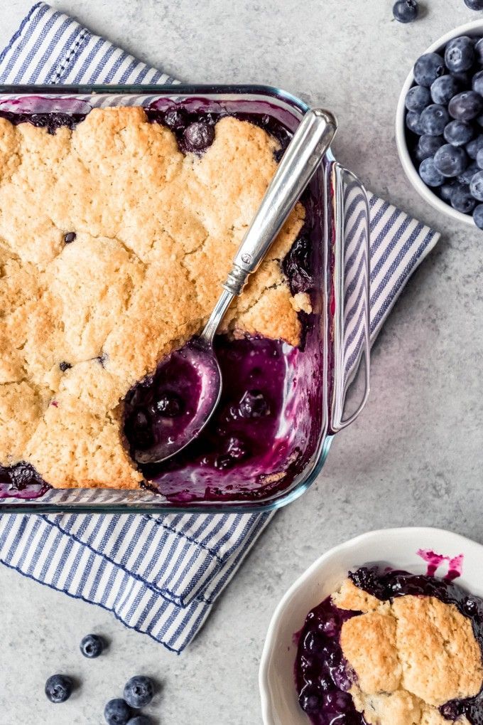 a blueberry cobbler in a glass dish with a spoon