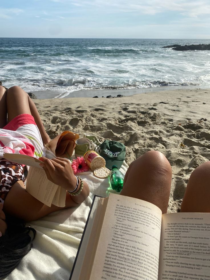 a person laying on the beach reading a book