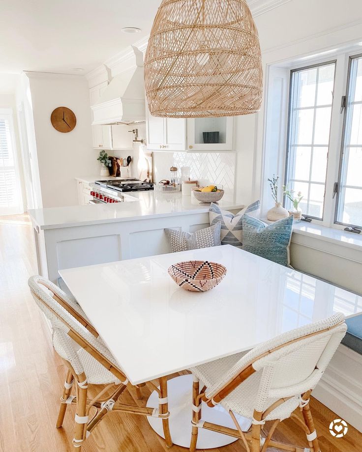 a white table and chairs in a room with a window on one side and a basket hanging from the ceiling