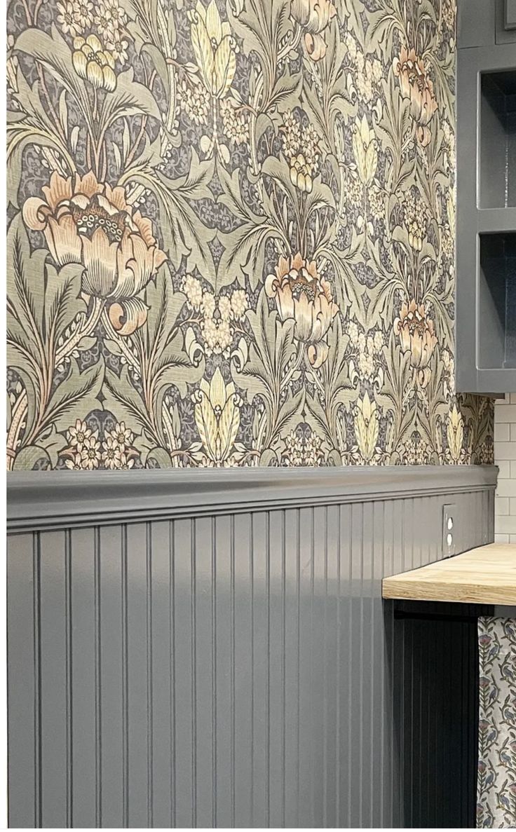 a kitchen with gray cabinets and wall paper