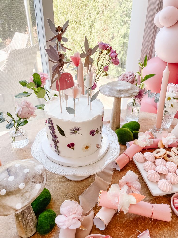 a table topped with a cake covered in frosting and lots of pink candies