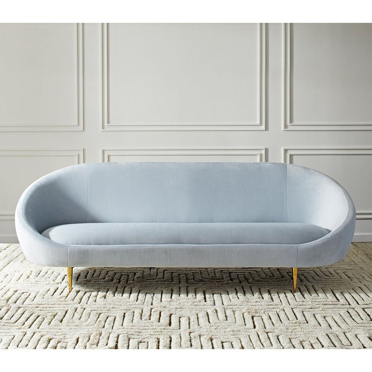 a light blue couch sitting on top of a rug next to a white wall and floor