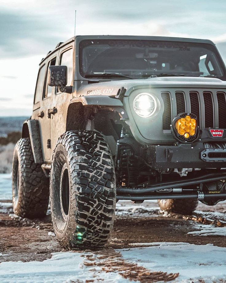 a jeep is parked in the snow with its lights on