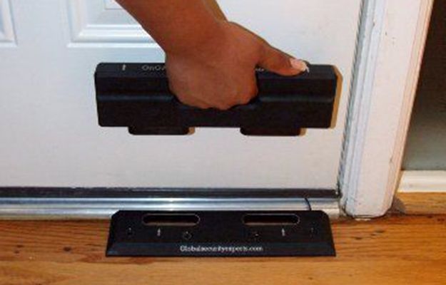 a person standing on top of a wooden floor next to a door holding onto a black object