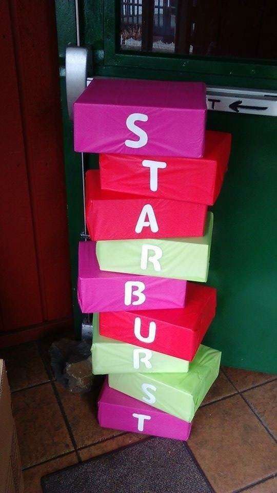 a stack of pink and green boxes with the word star burst on them sitting in front of a door