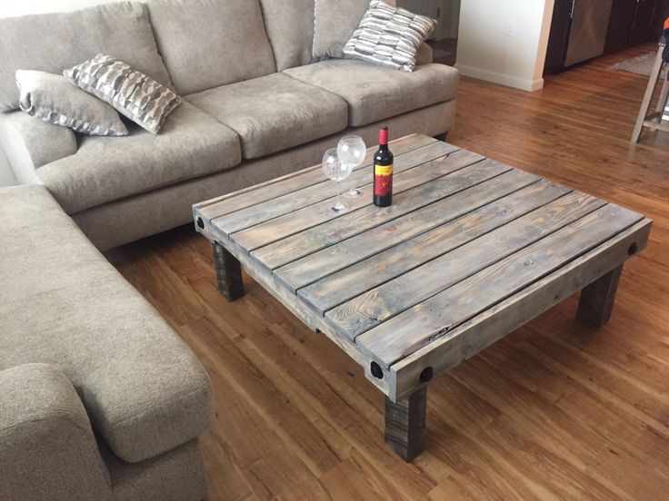 a living room with a couch, coffee table and wine bottle on the wooden floor