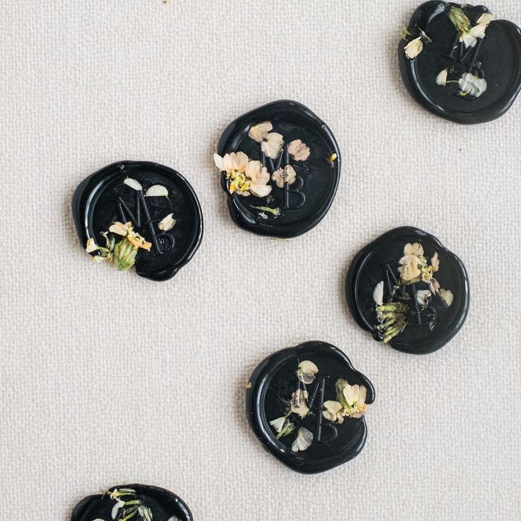 five black plates with flowers on them sitting on a table