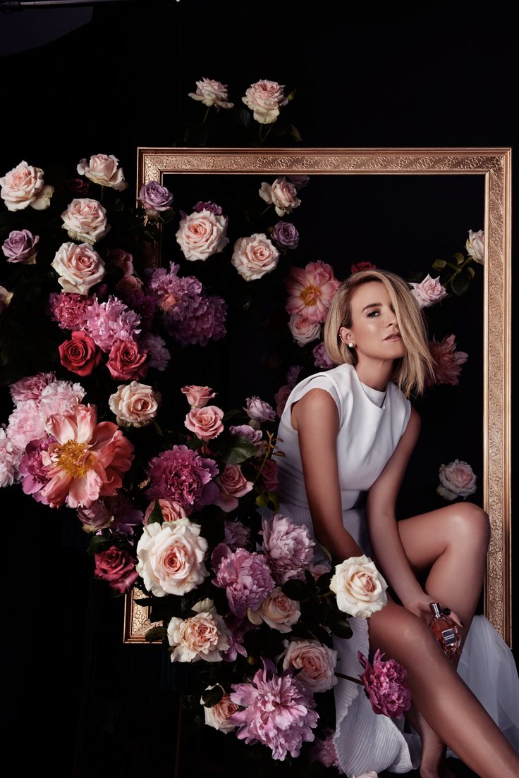 a woman is sitting in front of flowers