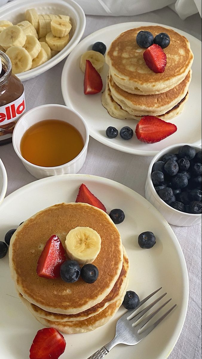 pancakes with fruit, bananas and syrup are on the table ready to be eaten for breakfast