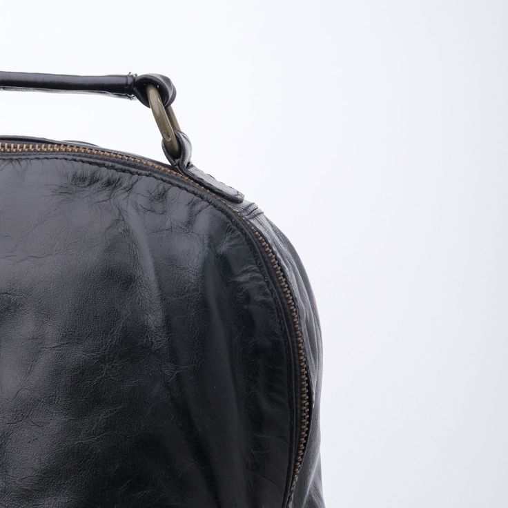 a black leather purse is shown against a white background, with the handle still attached to it