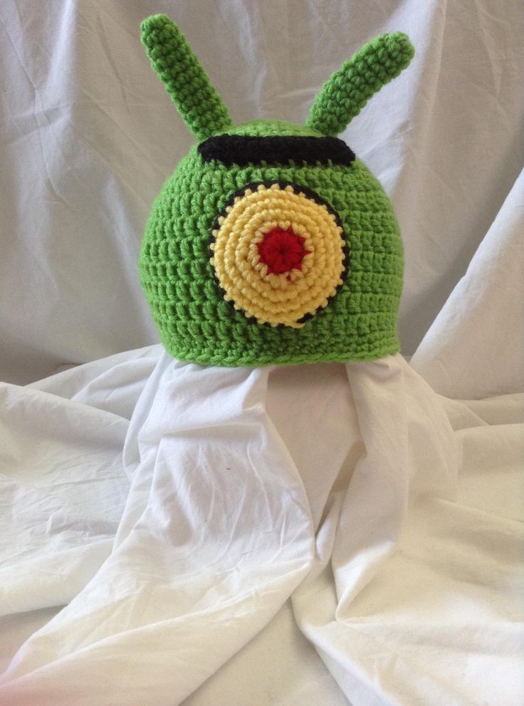 a green crocheted hat with a red eye