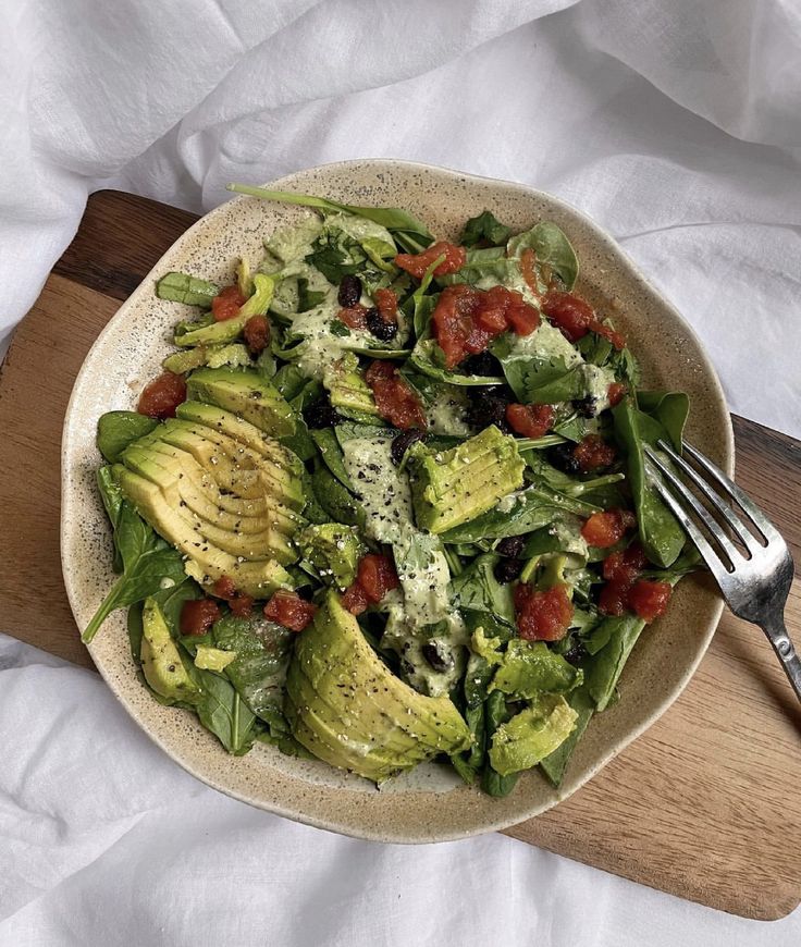 a salad with avocado, tomatoes and spinach